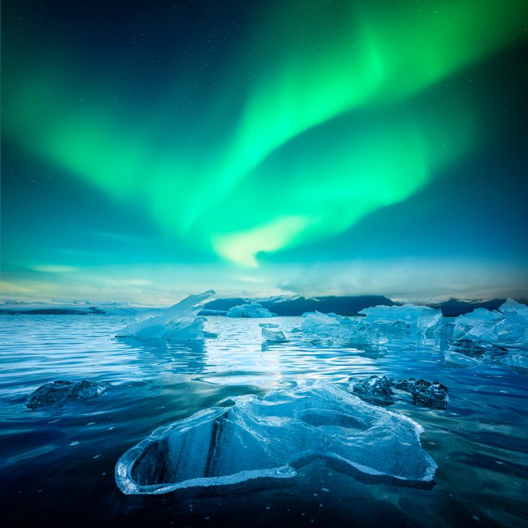 Icebergs in Jokulsarlon Glacial Lagoon under incredible night sky with Aurora Borealis in Iceland. Gorgeous Icelandic landscape with icebergs and Northern lights. Polar lights